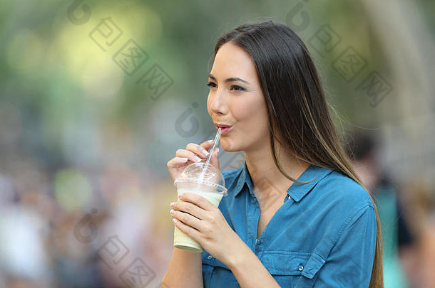 幸福的女人在街上走着，喝着奶昔