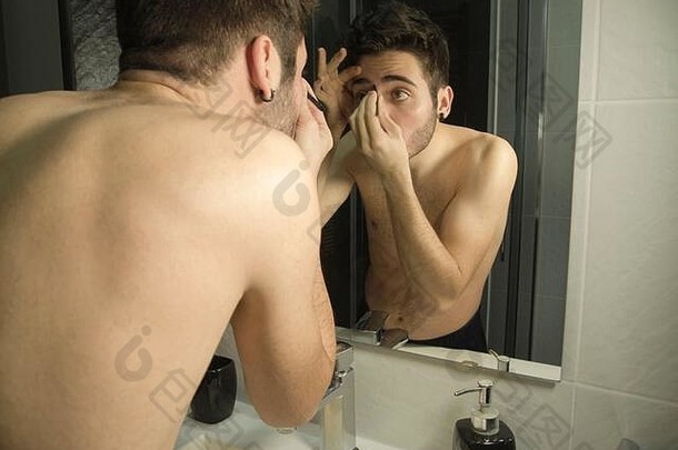 肖像英俊的高加索人少年反射镜子打蜡眉毛镊子每天护理概念
