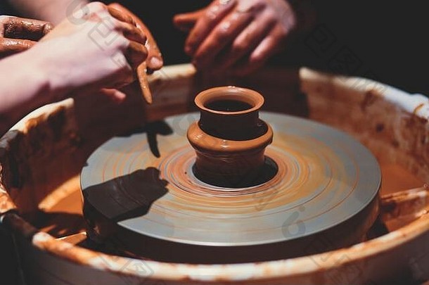 这是一个制作陶器的过程，有两个人参与其中，一个是制作陶轮，另一个是制作陶土陶器
