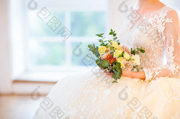 年轻漂亮的金发女人，带着花束，穿着婚纱摆姿势。闭合