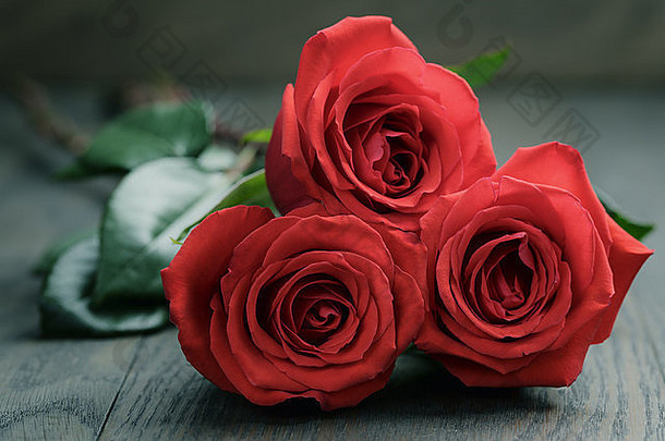 老橡木桌上放着三朵红玫瑰