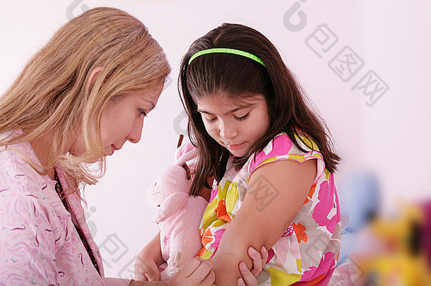 医生给女孩的手臂打针，把注意力集中在小女孩身上。