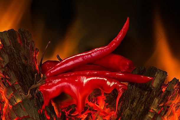 燃烧着的圆木上的红辣椒在背景中随着火焰融化。