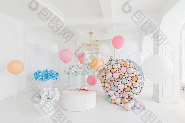 房间里摆放着鲜花盒和一个大布迪里尼萨，里面有球和气球，装饰着生日派对。