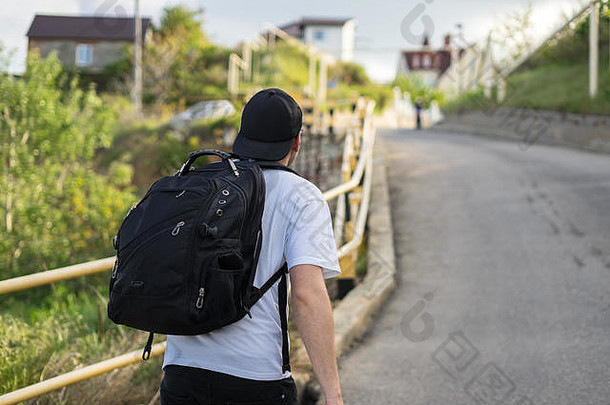 一个背着背包的时髦年轻人独自走在山路上