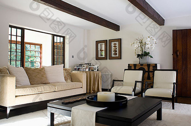 现代别墅客厅的奶油色沙发和椅子，配有黑色咖啡桌和奶油色地毯