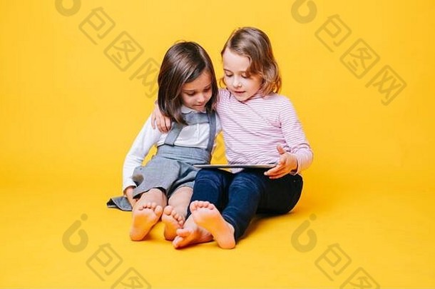 两个女孩使用黄色背景的数字平板电脑