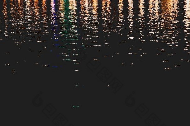 模糊色彩斑斓的灯反映水表面涟漪黑暗晚上摘要背景