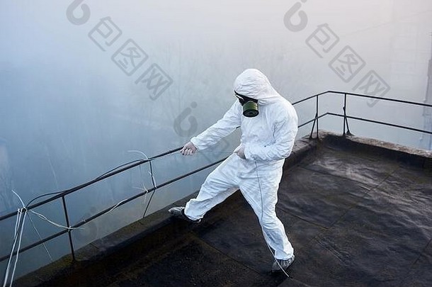 科学家在一幢高层建筑的屋顶上工作，穿着防护服和防毒面具，周围能见度很低
