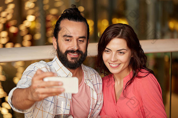 一对夫妇在餐厅用智能手机自拍