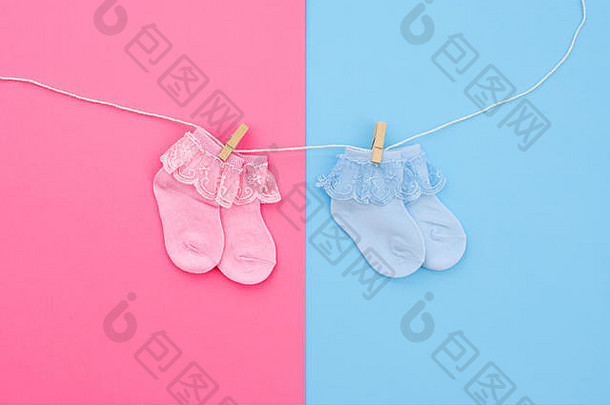 一对蓝色的粉红色的可爱的婴儿袜子挂晾衣绳蓝色的粉红色的背景婴儿配件平躺