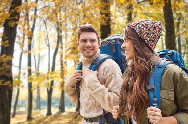微笑的夫妇背着背包在秋天远足
