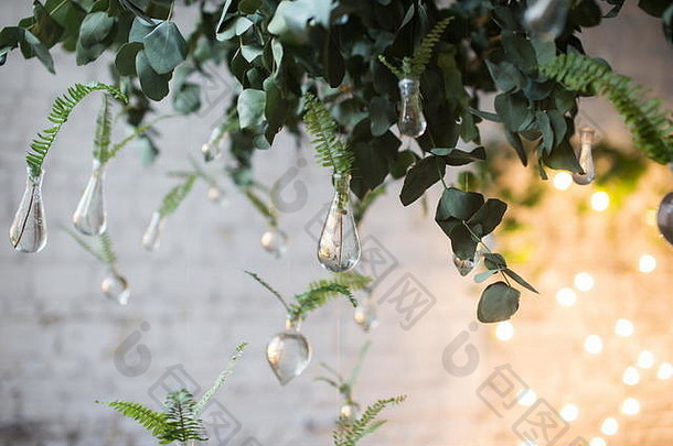 悬挂在玻璃水管中的蕨类植物的绿色叶子。美丽的乡村婚礼装饰件。阁楼式婚礼。