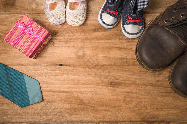 爸爸的靴子，婴儿的鞋子，纺织心形，礼物和木制背景上的蓝色领带。父亲节概念，复古色彩