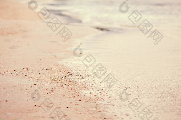 带有白色泡沫、沙滩背景和复印空间的海浪水特写镜头。采用复古电影效果风格滤镜，