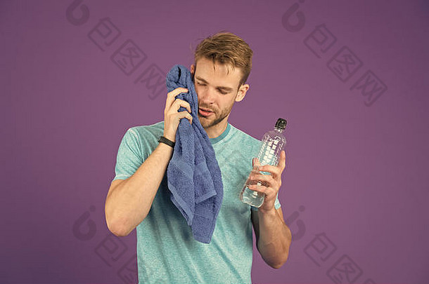运动员蓝色的T恤短裤毛巾培训男人。持有水瓶紫罗兰色的背景运动员塑料瓶渴脱水体育运动活动能源