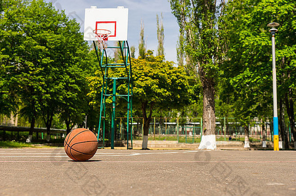 在绿树成荫的公园里，空荡荡的球场上，被遗忘的篮球