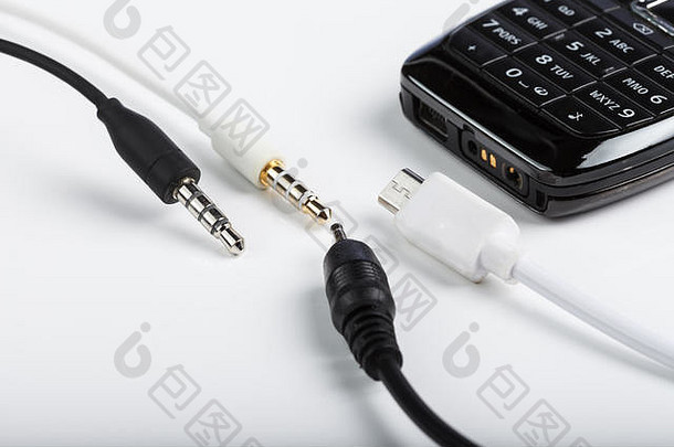 手机配件、插头、耳机、白色背景上隔离的连接器和带键盘的黑色电话