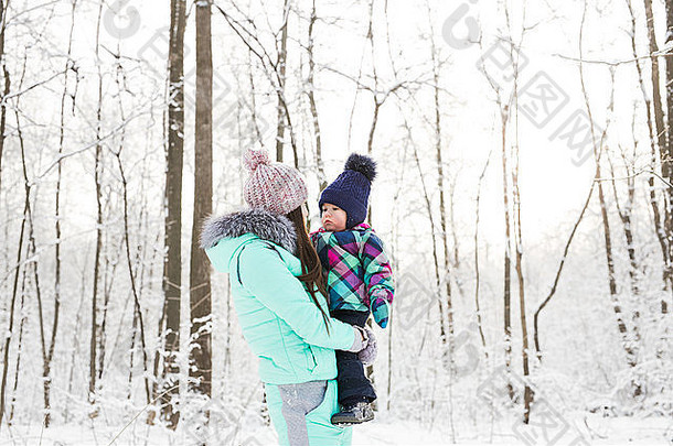 快乐家庭的母亲和孩子在森林里冬日散步
