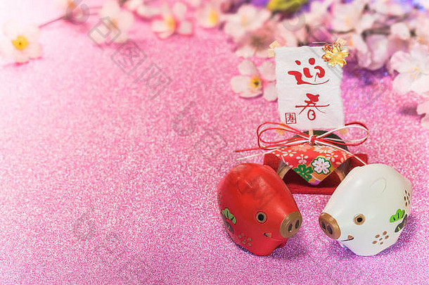 日本新年贺卡的亮丽背景是樱花，印有可爱的猪或猪的动物雕像和手写的宣纸