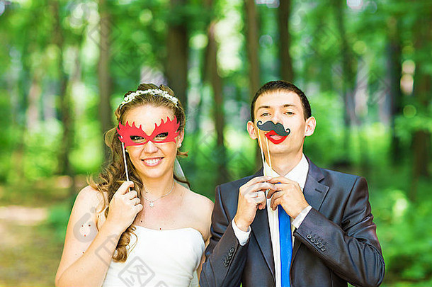 愚人节。新婚夫妇带着粘嘴唇、面具摆姿势。