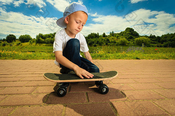 活跃的童年。小个子滑板。滑板男孩和他的滑板。户外的