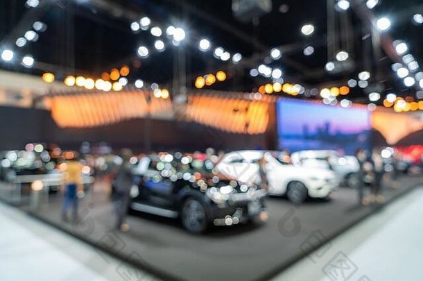 豪华展厅中展示的新车背景模糊，灯光闪烁，车展活动。