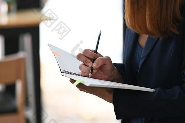 剪下了一张美丽的女士坐在舒适的咖啡馆里做秘<strong>书记</strong>笔记的照片作为背景。舒适的工作场所概念。