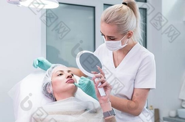 年轻的美容师医生准备使注射女嘴唇医生美容师使唇增加过程概念美