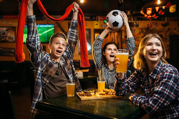 在运动酒吧，球迷们戴着围巾和球