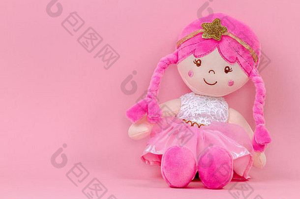 塞软娃娃坐着粉红色的背景
