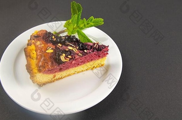 黑色的桌子上放着蓝莓<strong>慕斯</strong>蛋糕，白色盘子上有镜面釉装饰的浆果和薄荷叶。俯视图