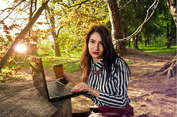 夏天或秋天，女孩坐在大自然中，拿着笔记本电脑