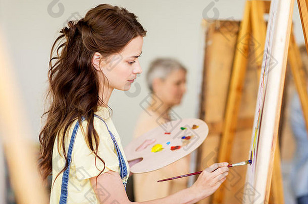在艺术学校用画架绘画的女学生