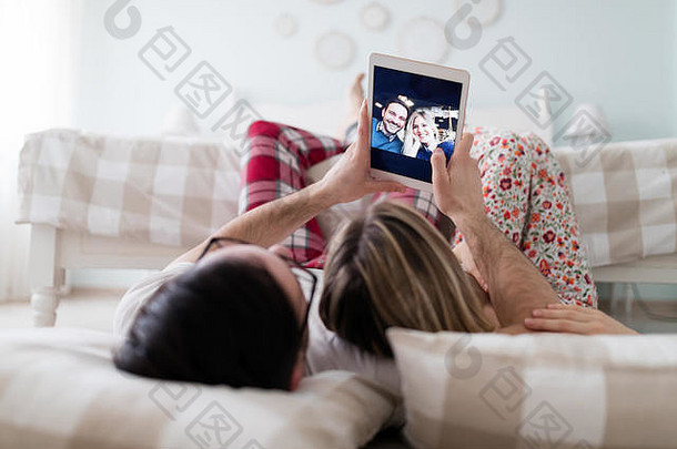 年轻迷人的夫妇在卧室里使用数码平板电脑