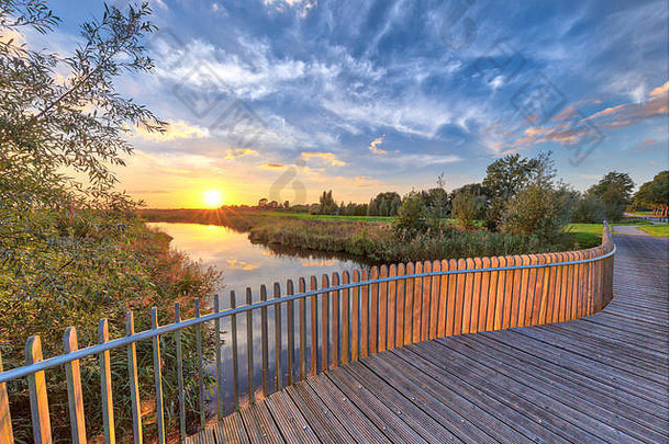 荷兰格罗宁根Onlanden自然保护区内涝区桥上木栏杆阳台上明亮的日落