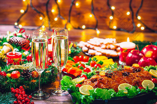 圣诞餐桌晚餐时间，烤肉装饰成圣诞风格，酒杯香槟。背景感恩节。家庭的概念