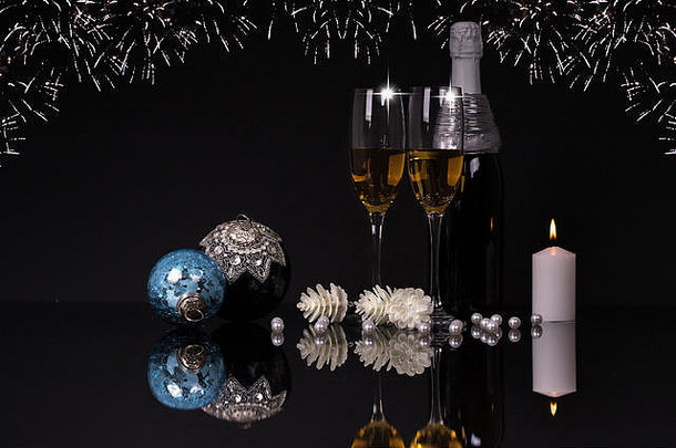 两个酒杯，配香槟、蜡烛和圣诞装饰品，黑色背景，反光。空间。圣诞快乐，新年快乐，