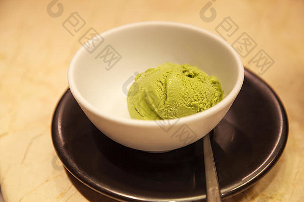 新鲜可口的抹茶绿茶味冰淇淋，放在桌子背景的白碗里。健康糖果、夏季甜点、放纵、零食、营养品