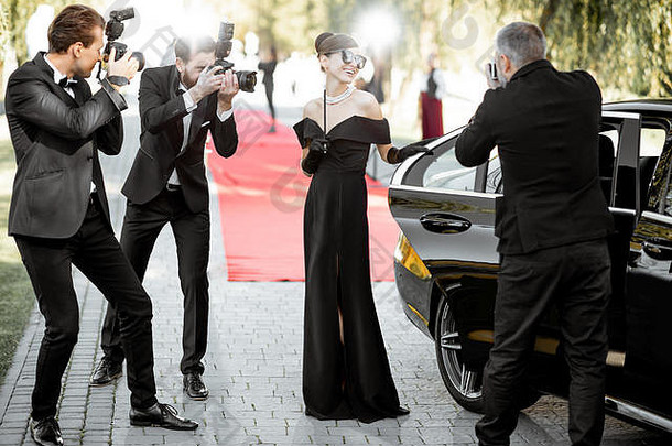 一位身着复古风格的著名电影女演员来到颁奖典礼现场，摄影记者为她拍照