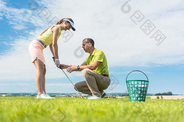 在教练的帮助下练习高尔夫挥杆的年轻女子