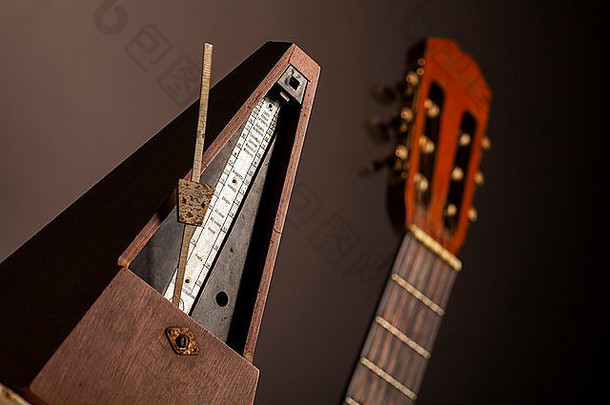 黑色背景上，古典节拍器的彩色照片，靠近原声吉他。