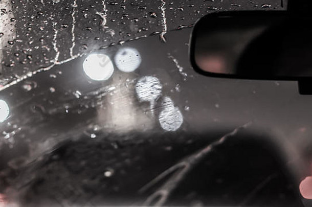 下雨时汽车的内部。雨天路上散焦模糊的光线