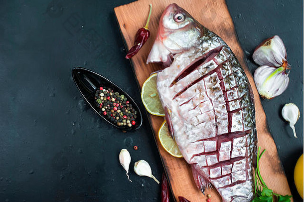 深色复古背景上的美味鲜鱼。含香料、香料和蔬菜的鱼类-健康食品、饮食或烹饪理念