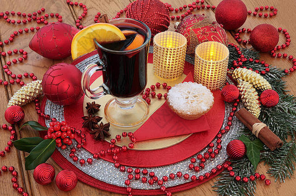 圣诞热葡萄酒、肉馅饼、红色和金色装饰品、蜡烛、水果和香料、冬青树和雪覆盖的冷杉。