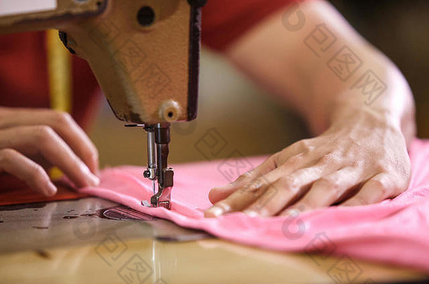 在一家制衣厂，男人的手在缝纫机上缝纫