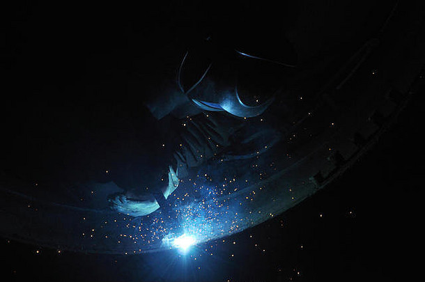 专业焊工在车间焊接工业储罐。