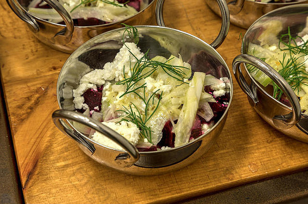 山羊奶酪和红甜菜色拉装在不锈钢小碗里。
