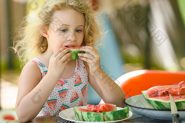 可爱的金发小女孩，夏天在户外吃西瓜
