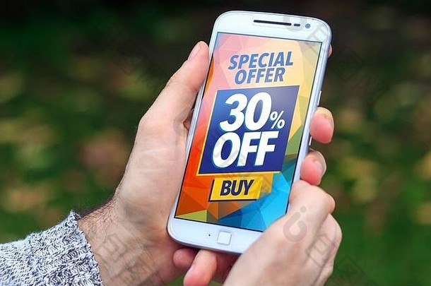 一个男人拿着一部智能手机，屏幕上有30%的折扣广告。营销、电子商务、手机宣传。